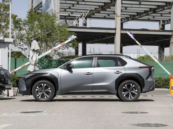 Side detail view of a gray Toyota BZ4X electric car with skyscrapers in the background.