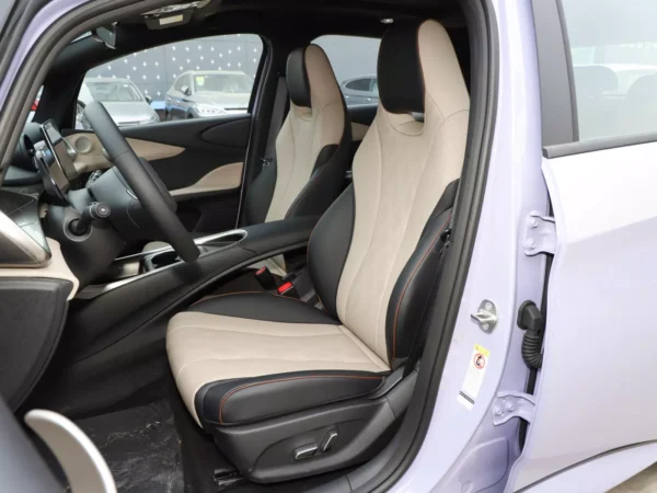 Close-up view of the interior cabin of the lavender BYD Dolphin electric car with the front doors open to reveal the steering wheel and seats inside.