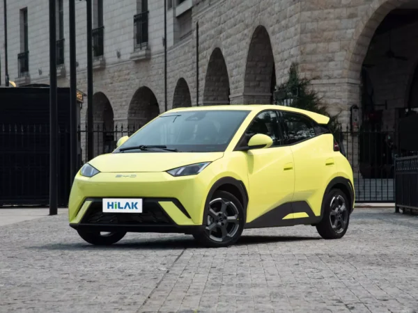 Left front view of a yellow BYD Seagull electric car with a black iron fence in the background.