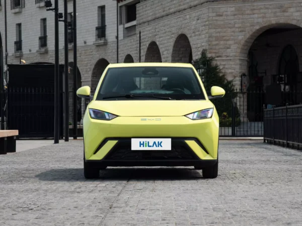 Front view of a yellow BYD Seagull electric car parked on a brick pavement.