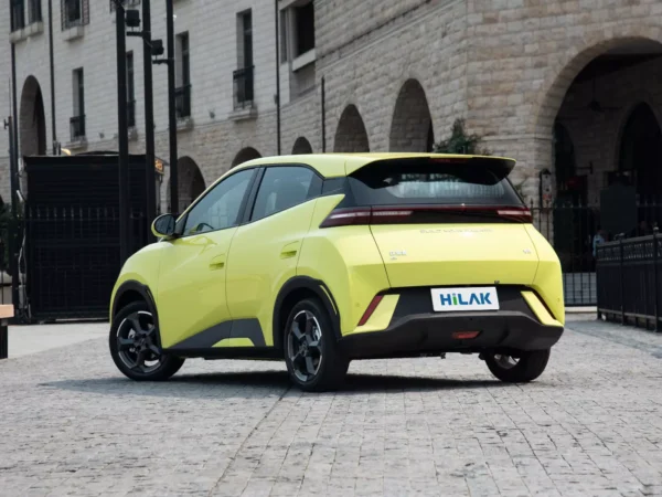 A left rear view of a yellow BYD Seagull electric car with the vehicle parked on a gray brick road.