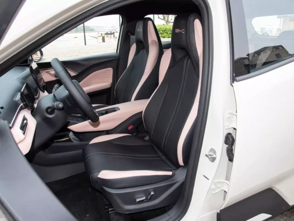 Detailed view of the cab of a white BYD Seagull electric car with open doors and black and pink interior colors.