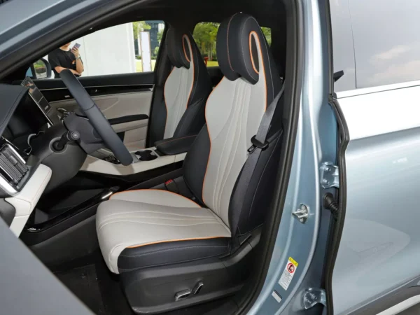 A picture of a BYD Song Plus electric car with the driver's door open, the interior trim colors of the cab are grey and black with orange line trim.