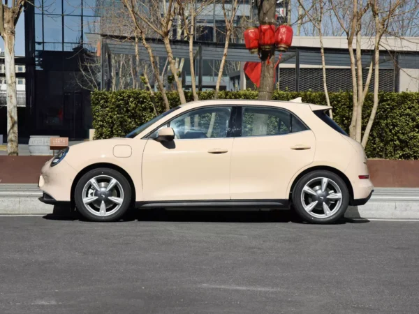 A cream-colored Ora Ballet Cat electric car pulls up to the curb next to residential buildings decorated with lanterns.